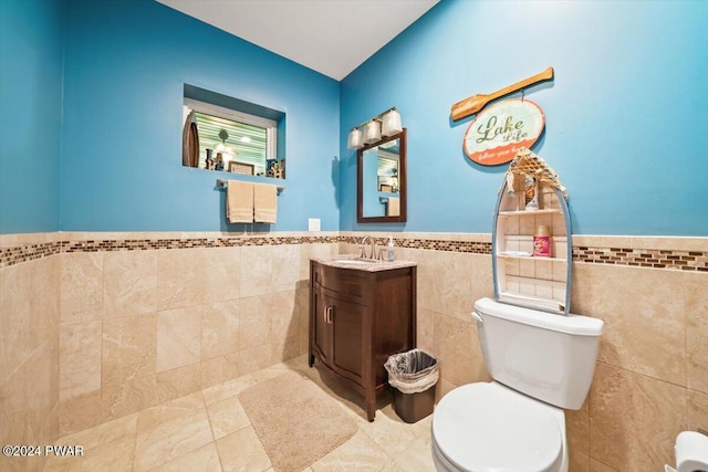 bathroom with tile patterned floors, vanity, tile walls, and toilet