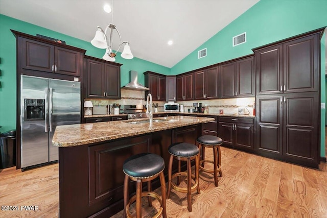 kitchen with wall chimney range hood, decorative backsplash, sink, and stainless steel refrigerator with ice dispenser