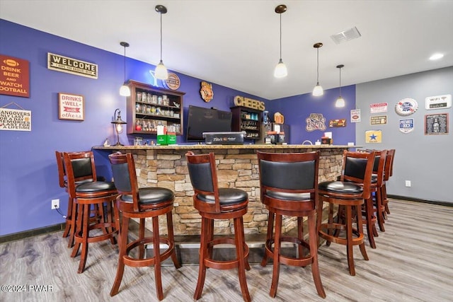 bar featuring light hardwood / wood-style flooring and decorative light fixtures