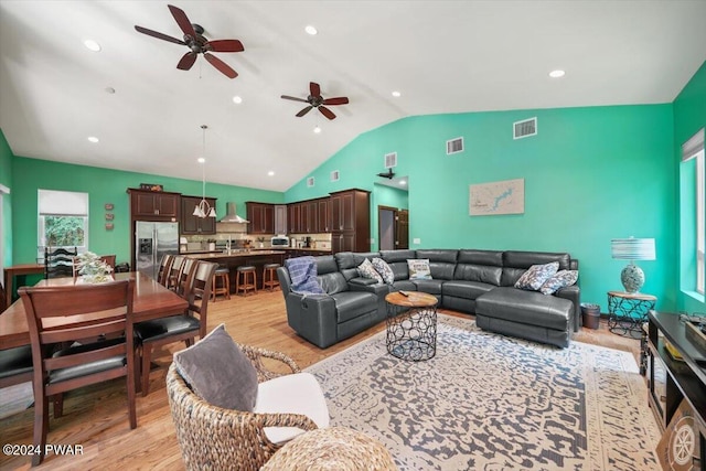 living room featuring ceiling fan, vaulted ceiling, and light wood-type flooring