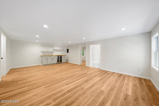 unfurnished living room featuring light hardwood / wood-style flooring and beverage cooler