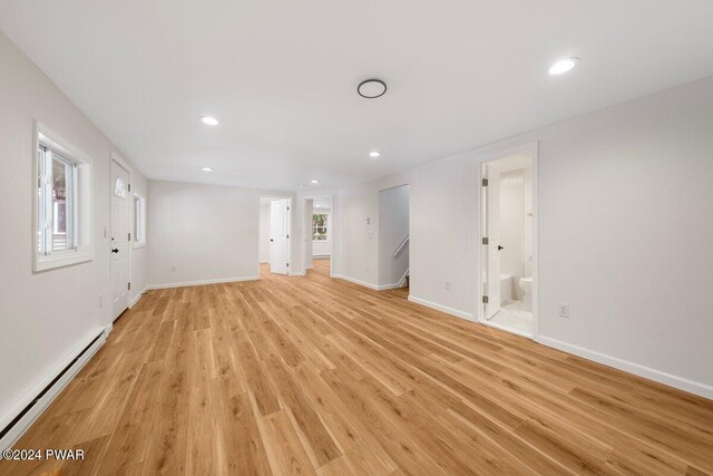 unfurnished living room featuring plenty of natural light, light hardwood / wood-style floors, and a baseboard radiator