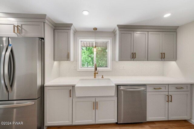 kitchen featuring backsplash, stainless steel appliances, gray cabinetry, and sink