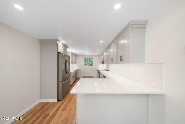 kitchen featuring kitchen peninsula, white cabinetry, stainless steel refrigerator, and light hardwood / wood-style flooring