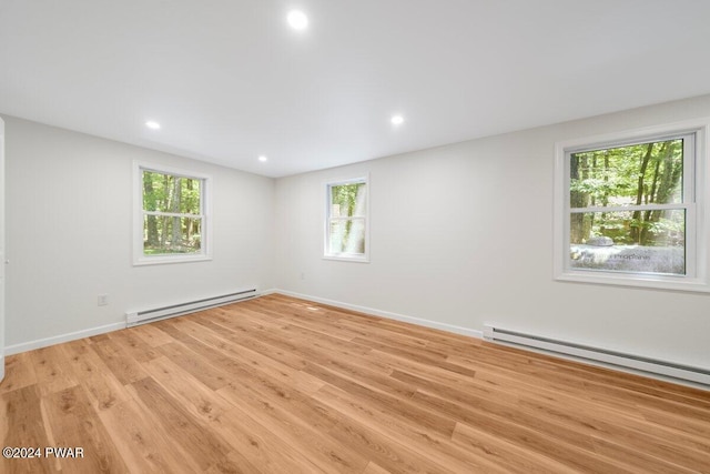 unfurnished room featuring light hardwood / wood-style floors and a baseboard heating unit