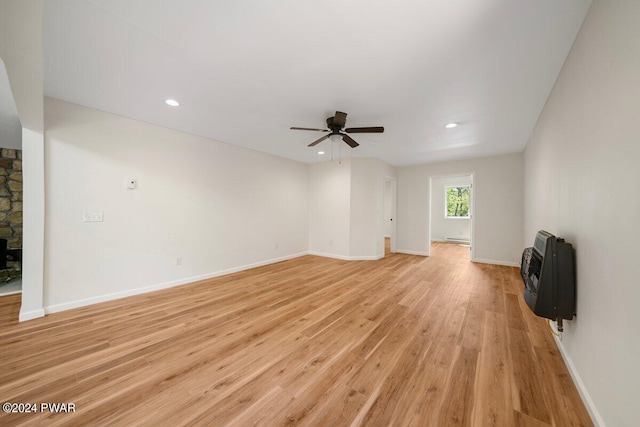 unfurnished living room with heating unit, ceiling fan, and light wood-type flooring