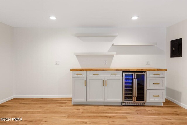 bar with electric panel, white cabinetry, beverage cooler, and wood counters