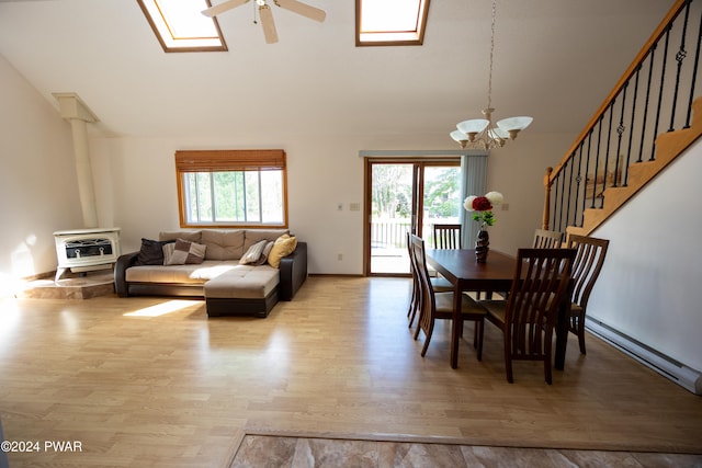 dining space featuring ceiling fan with notable chandelier, heating unit, vaulted ceiling, baseboard heating, and light hardwood / wood-style floors