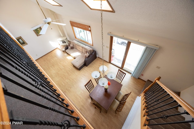 unfurnished living room featuring ceiling fan, wood-type flooring, a textured ceiling, and high vaulted ceiling