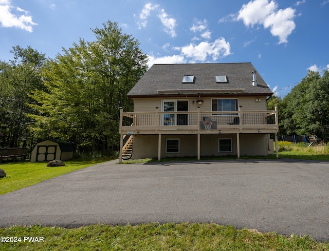 rear view of house with a lawn, a storage shed, and a wooden deck