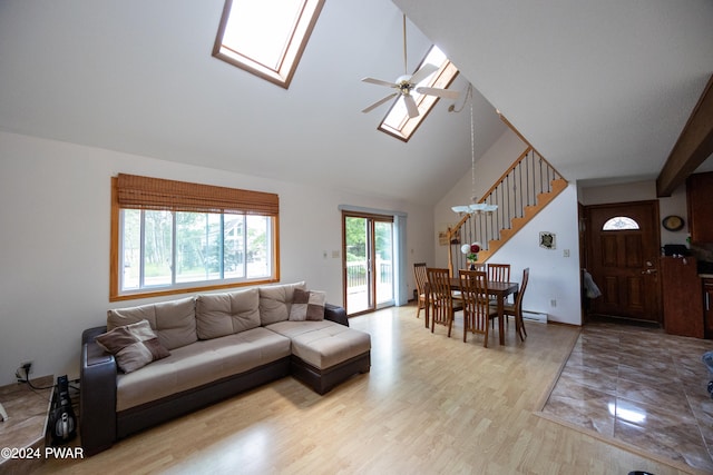 living room with light wood-type flooring, a skylight, high vaulted ceiling, and ceiling fan