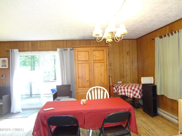115 Eastwood Dr, Greentown, PA 18426 - dining space with a baseboard heating unit, a chandelier, wood walls, and light wood-type flooring