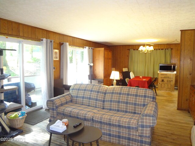 115 Eastwood Dr, Greentown, PA 18426 - living room featuring a chandelier, wooden walls, light wood finished floors, and a baseboard heating unit