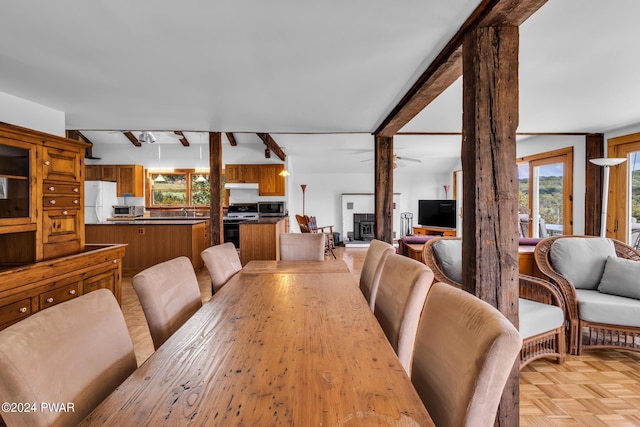 dining room featuring beamed ceiling, a wood stove, and light parquet floors