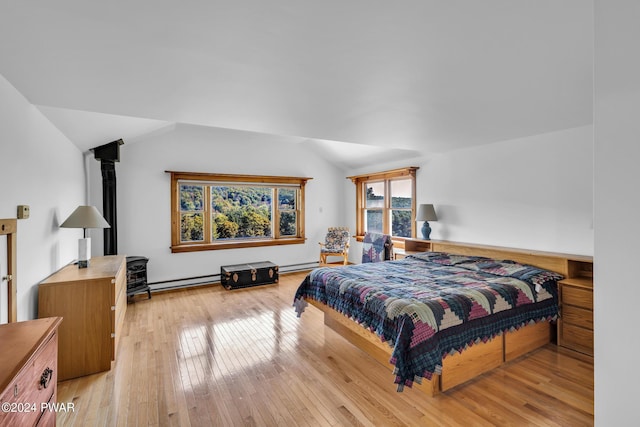 bedroom with light wood-type flooring, vaulted ceiling, and a baseboard heating unit