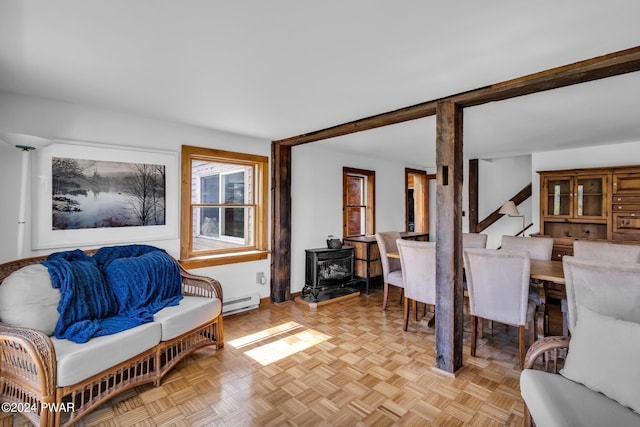 living room with light parquet flooring, a wood stove, and a baseboard heating unit