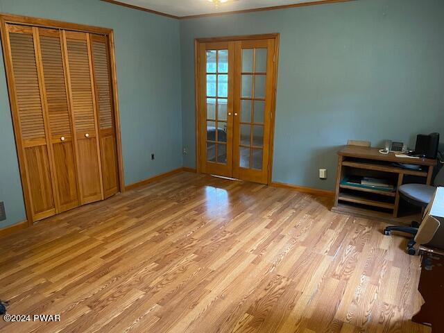 unfurnished office featuring light wood-type flooring, crown molding, and french doors