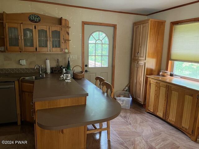 kitchen with dishwasher, sink, light tile patterned floors, and ornamental molding