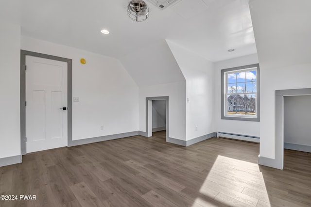 unfurnished living room featuring light wood-type flooring, baseboard heating, and vaulted ceiling