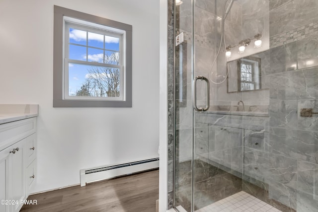 bathroom with hardwood / wood-style floors, vanity, a shower with door, and a baseboard heating unit