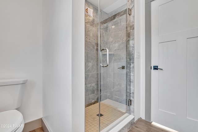 bathroom with an enclosed shower, toilet, and wood-type flooring