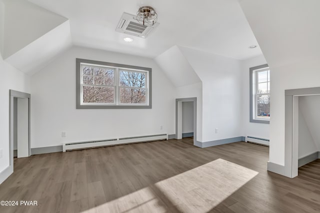 additional living space featuring a healthy amount of sunlight, light hardwood / wood-style flooring, and a baseboard heating unit