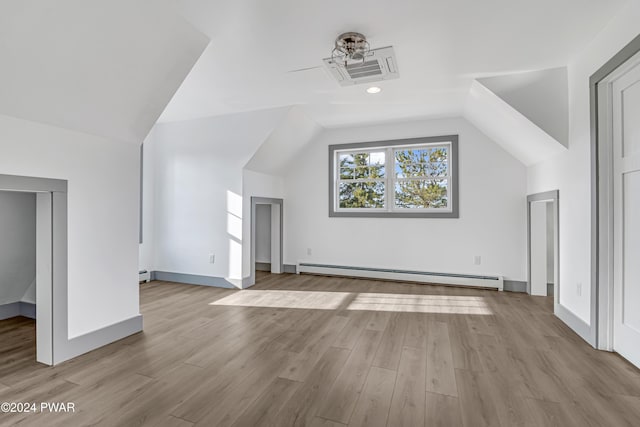 additional living space with light wood-type flooring, baseboard heating, and lofted ceiling