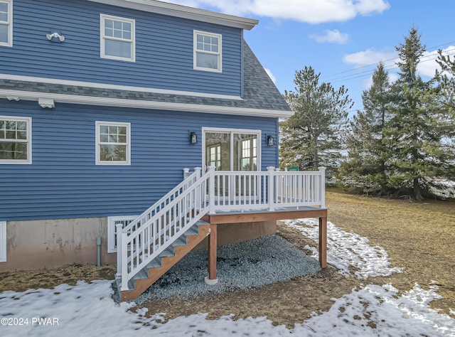 snow covered back of property featuring a deck