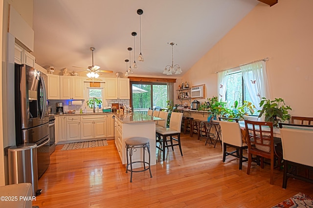 127 E Mulberry Dr, Milford, PA 18337 - kitchen featuring stainless steel appliances, high vaulted ceiling, a breakfast bar area, decorative backsplash, and light wood finished floors