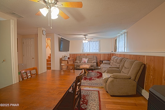 127 E Mulberry Dr, Milford, PA 18337 - living area with ceiling fan, a textured ceiling, light wood finished floors, stairway, and a wainscoted wall