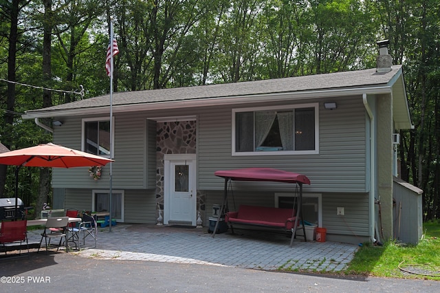 127 E Mulberry Dr, Milford, PA 18337 - split foyer home with a patio area, a chimney, a shingled roof, and view of wooded area