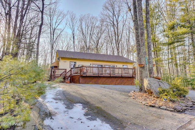 view of front of home featuring aphalt driveway, a deck, and stucco siding