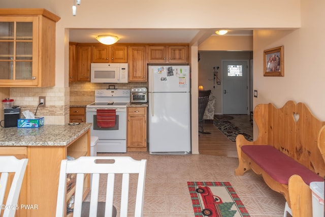 kitchen with tasteful backsplash, white appliances, and light stone countertops