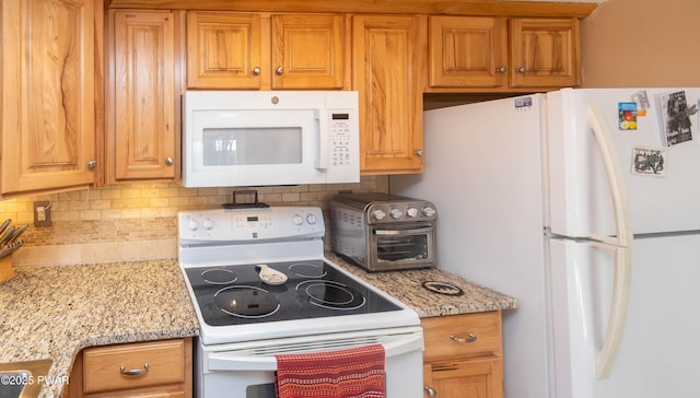 kitchen with light stone counters, white appliances, and tasteful backsplash