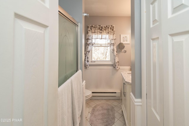 bathroom with a shower with door, tile patterned flooring, a baseboard heating unit, vanity, and toilet