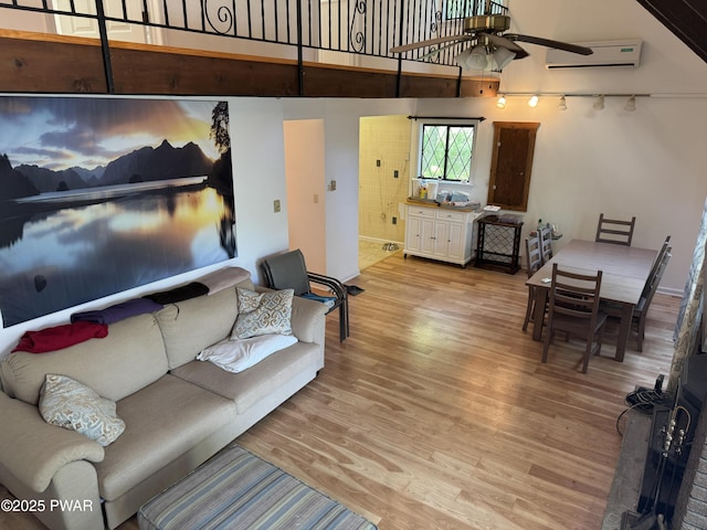 219 Woodpecker Ct, Bushkill, PA 18324 - living area featuring light wood-style floors, a ceiling fan, a towering ceiling, and a wall unit AC