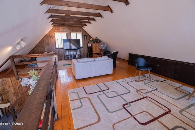 living room with wooden walls, lofted ceiling with beams, and hardwood / wood-style floors