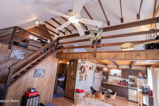 kitchen featuring white appliances, wooden walls, a ceiling fan, vaulted ceiling with beams, and light wood-type flooring