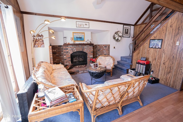 living room with stairway, wooden walls, wood finished floors, vaulted ceiling, and crown molding