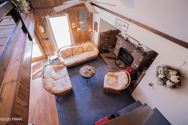 living room with a brick fireplace, wooden walls, and ceiling fan