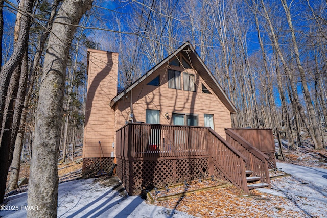 snow covered property featuring a wooden deck and a chimney