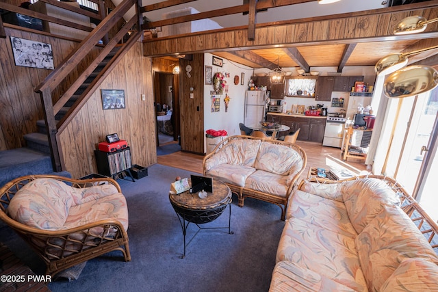 living area with beamed ceiling, wood walls, and stairs