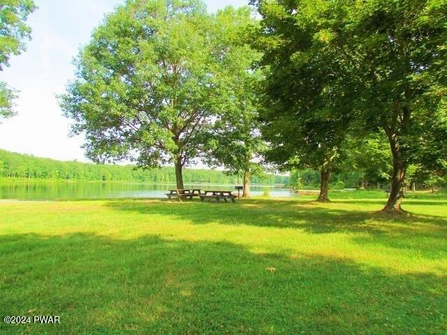 view of property's community featuring a lawn and a water view