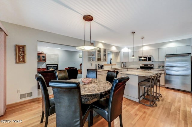 dining room with sink, a fireplace, and light hardwood / wood-style flooring