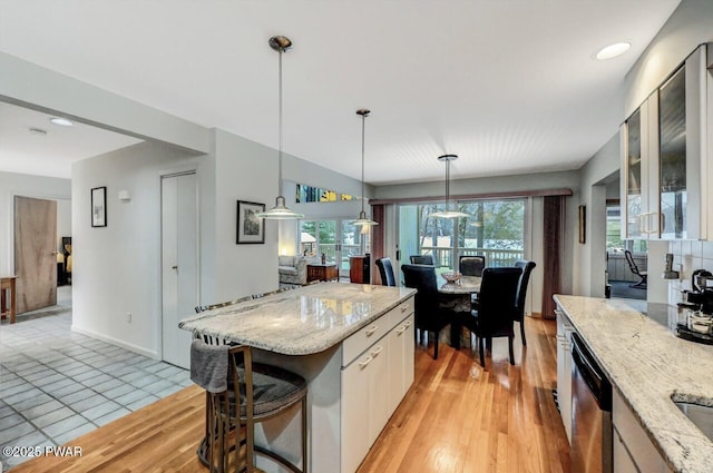 kitchen featuring white cabinetry, a kitchen island, light stone counters, and decorative light fixtures