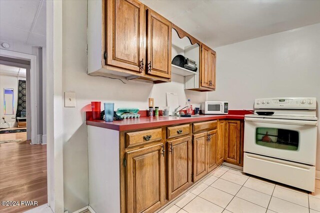 kitchen featuring light tile patterned flooring, white appliances, and sink