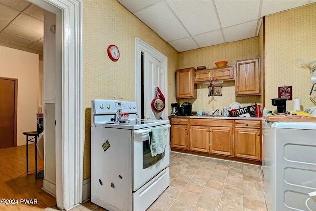 kitchen with electric range, a drop ceiling, washer / dryer, and sink