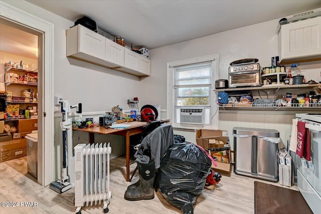 kitchen with white cabinets, cooling unit, radiator, and light hardwood / wood-style flooring