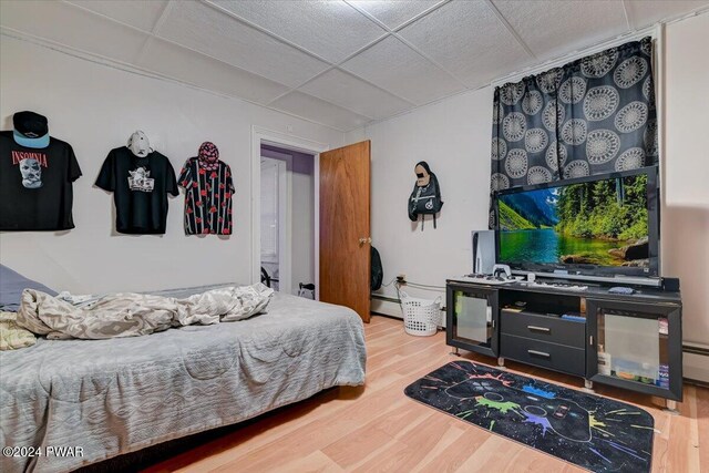 bedroom with hardwood / wood-style flooring, a drop ceiling, and a baseboard radiator