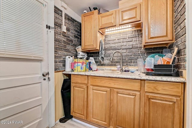 kitchen with sink, brick wall, and tasteful backsplash